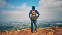 Man Standing At The Edge Of A Cliff And Staring At Clouds