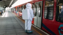 An astronaut is standing on a railway platform waiting for the coach to get open. 