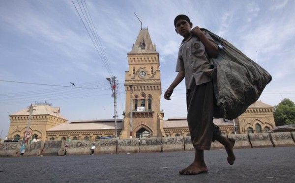 A barefooted boy carries a sack for recyclable materials as he walks past the British era Empress Market building in Karachi April 8, 2012. The Empress Market was constructed between 1884 and 1889 and was named to commemorate Queen Victoria, Empress of India. REUTERS/Akhtar Soomro (PAKISTAN - Tags: SOCIETY BUSINESS EMPLOYMENT ENVIRONMENT)