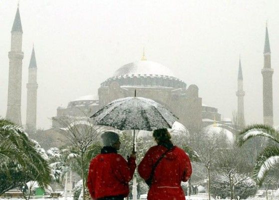 Tourists admire the sixth-century Byzantinian monument of St. Sofia (Ayasofia) as they walk past the snow covered palm trees in the old city in Istanbul February 8, 2003. NO RIGHTS CLEARANCES OR PERMISSIONS ARE REQUIRED FOR THIS IMAGE REUTERS/Fatih Saribas FS/CRB