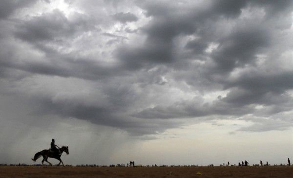 A horse rider is silhouetted against the pre-monsoon clouds at Marina beach