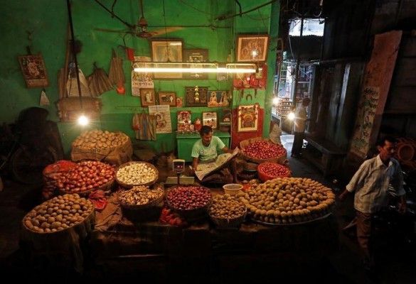 A vendor reads a newspaper at his vegetable shop as he waits for customers in Kolkata, September 12, 2016. REUTERS/Rupak De Chowdhuri