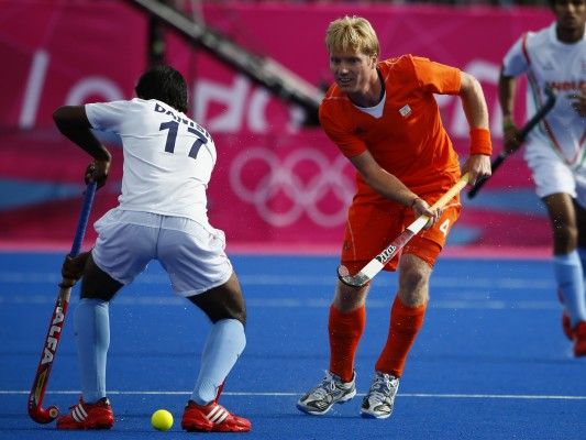 Netherlands' Klaas Vermeulen hits the ball through the legs of India's Danish Mujtaba during their men's Group B hockey match at the London 2012 Olympic Games