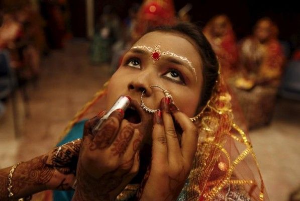 A bride gets her make-up done before the start of a mass marriage ceremony in Kolkata, India, February 14, 2016. A total of 150 tribal Hindu, Muslim and Christian couples from various villages across the state took their wedding vows on Sunday during the day-long mass marriage ceremony organised by a social organisation, the organisers said. REUTERS/Rupak De Chowdhuri TPX IMAGES OF THE DAY