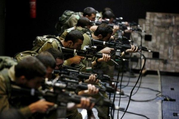 Israeli soldiers respond with laser-firing rifles to a simulated Palestinian attack playing out on an interactive screen, during an open-fire scenario training in Camp Tsur infantry training base in southern Israel, near Yeruham March 24, 2016. REUTERS/Amir Cohen