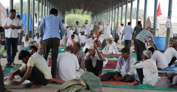 सीकर सब्जी मंडी में समूह में बैठे किसान, पास में आटा गूंथा जा रहा है