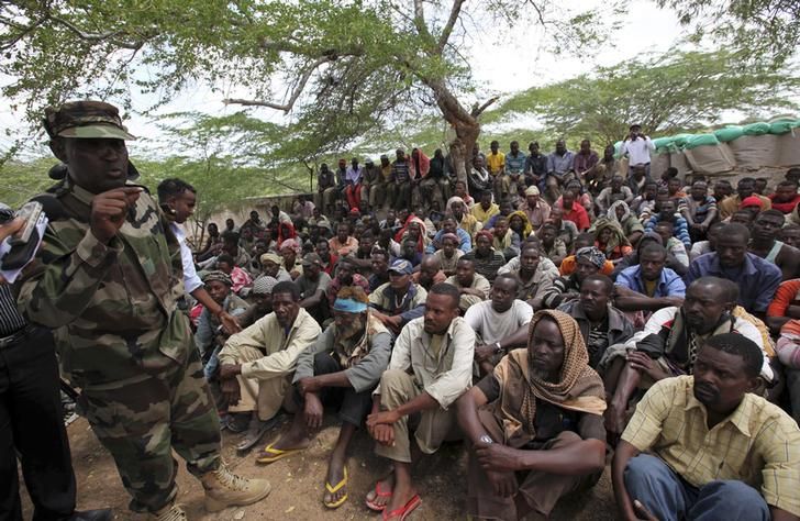 Members of al Qaeda-linked militant group al Shabab listen to a Somalia government soldier as they are paraded at Maslah square after their surrender to the authorities in the north of Somalia's capital Mogadishu September 24, 2012. More than 200 members of the militant group surrendered to African Union and Somalia government soldiers on Saturday. The move will likely bolster government and Africa Union preparations for an onslaught on the southern city of Kismayu - currently the last bastion of the militant group. REUTERS/Omar Faruk (SOMALIA - Tags: POLITICS CIVIL UNREST)