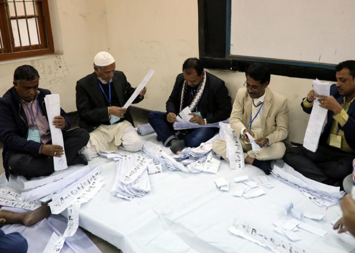 Presiding officers count votes at a voting center after the session has ended in Dhaka