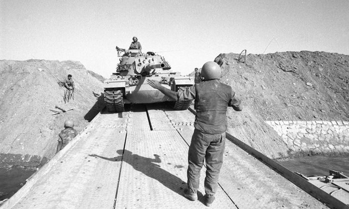 1973 में इज़रायल और खाड़ी देशों में अच्छा ख़ासा तनाव हो गया था. तनाव जो अक्टूबर में 20 दिन लंबे युद्ध में परिवर्तित हो गया. इस सबके चलते ओपेक ने अमेरिका पर भी प्रतिबंध लगा दिया. और तेल के दाम बढ़ने लगे. कितने बढ़ने लगे? 3 डॉलर से बढ़कर 12 डॉलर हो गए. (तस्वीर में: इज़रायल के सैनिक स्वेज़ कनाल क्रॉस करते हुए. By Israel Defense Forces, CC BY-SA 2.0, https://commons.wikimedia.org/w/index.php?curid=34369608)