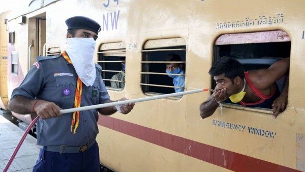 श्रमिक ट्रेन में सवार लोगों को पानी पिलाता एक स्काउट गाइड. (Photo: PTI)
