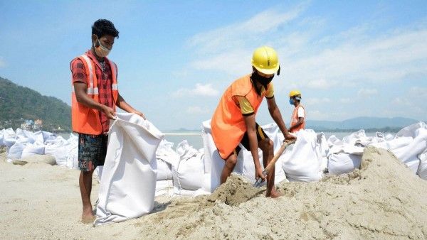 असम में ब्रह्मपुत्र नदी के किनारे में काम में जुटे हुए मजदूर. (Photo: PTI)