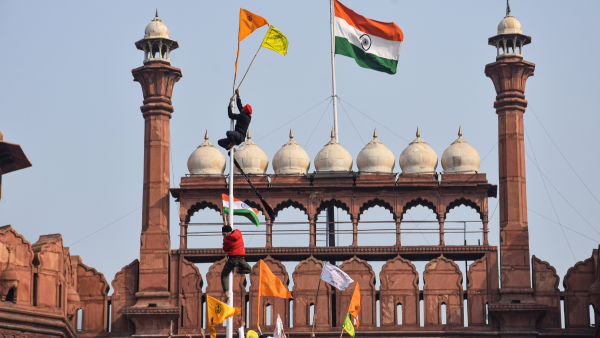 लाल किले में किसान आंदोलन में शामिल एक आदमी झंडा फहराते हुए. (फोटो- PTI) Tractor Rally (3)