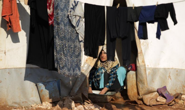 सीरियाई-तुर्की सीमा के पास अपने तंबू के अंदर कपड़े धोती हुई एक विस्थापित सीरियाई महिला (फोटो - रॉयटर्स) Women In Syria