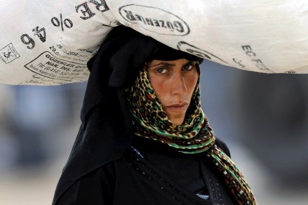 A Syrian refugee woman carries her belongings as she crosses into Turkey at Akcakale border gate in Sanliurfa province, Turkey